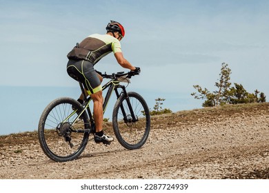 athlete cyclist riding mountain bike uphill, biking on gravel road, cycling competition - Powered by Shutterstock