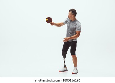 Athlete With Disabilities Or Amputee Isolated On White Studio Background. Professional Male Table Tennis Player With Leg Prosthesis Training In Studio. Disabled Sport And Healthy Lifestyle Concept.