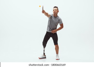 Athlete With Disabilities Or Amputee Isolated On White Studio Background. Professional Male Table Tennis Player With Leg Prosthesis Training In Studio. Disabled Sport And Healthy Lifestyle Concept.