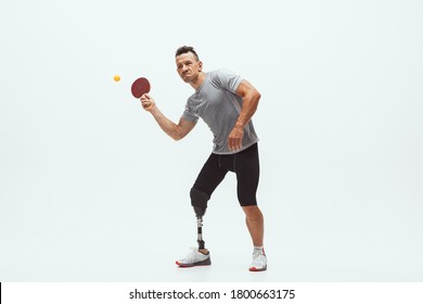 Athlete With Disabilities Or Amputee Isolated On White Studio Background. Professional Male Table Tennis Player With Leg Prosthesis Training In Studio. Disabled Sport And Healthy Lifestyle Concept.