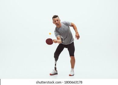 Athlete With Disabilities Or Amputee Isolated On White Studio Background. Professional Male Table Tennis Player With Leg Prosthesis Training In Studio. Disabled Sport And Healthy Lifestyle Concept.