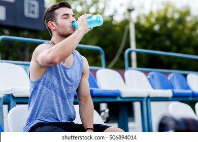 Athlete drinking from plastic bottle of water after workout outdoors