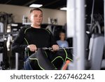 Athlete is engaged in the simulator - develops biceps and triceps