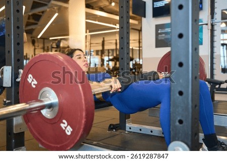 Athlete executing hip thrusts with a barbell in a contemporary fitness center, focusing on strength training and muscle building