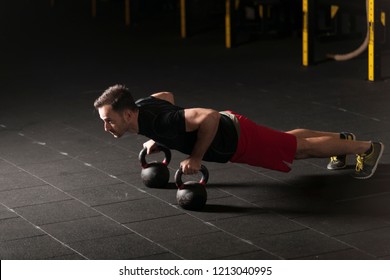 Athlete exercising push ups on kettlebells at the gym. Dark photography concept with copy space. - Powered by Shutterstock