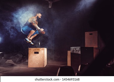 Athlete gave exercise. Jumping on the box. Phase touchdown. Gym shots in the dark tone. Smoke in gym.