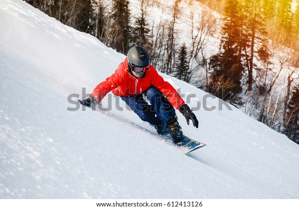 athlete with a hard snowboard for slalom in a ski\
resort enters the turn, Murmansk region, Russia. Shine of the sun.\
Toning.