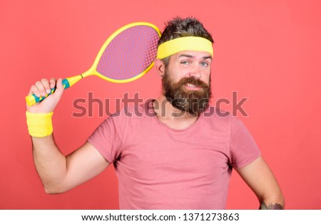 Athlete hipster hold tennis racket in hand red background. Play tennis for fun. Reach top again. Man bearded hipster wear sport outfit. Tennis player retro fashion. Tennis sport and entertainment.