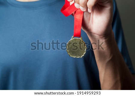 Athlete holding gold medal with his hands. Medal concept.
