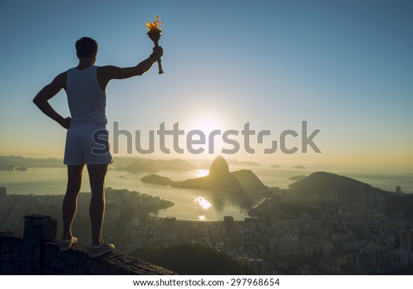 Athlete\
holding sport torch standing in silhouette against Rio de Janeiro\
Brazil sunrise skyline with Sugarloaf\
Mountain