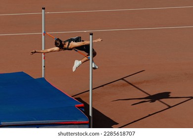 athlete jumper high jump in summer athletics competition, silhouette high jumper on red track stadium - Powered by Shutterstock