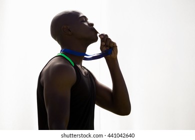 Athlete kissing his gold medal on white background - Powered by Shutterstock