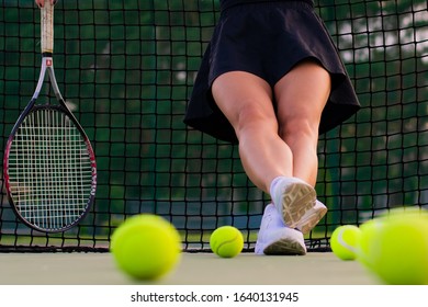 Athlete With Legs Kicked Up Scattered Balls On The Tennis Court