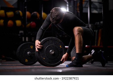 Athlete male adding weight plates on barbell, young caucasian fit guy preparing for weightlifting workout at gym alone. bodybuilding concept