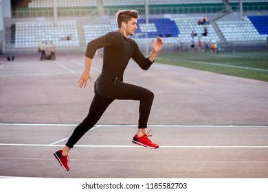 Athlete Man In Black Clothes Running On Track On Sunny Day