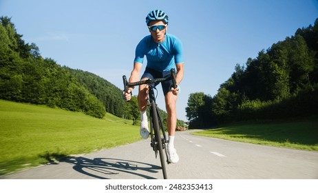 Athlete man in cycling blue jersey and gear, riding a professional racing cycle on the paved road