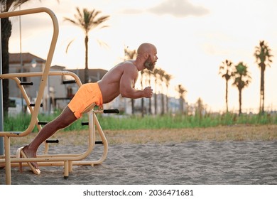 Athlete Man Practicing Calisthenics Outdoors On The Beach At Sunset.