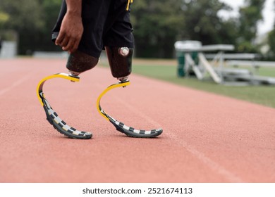 Athlete man with prosthetic legs running on a track. Para-athletes disabled with prosthetic blades running at stadium. Amputee man runner exercise and practicing on a track. - Powered by Shutterstock