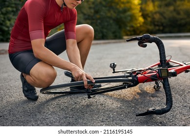 Athlete Man Repairs Bicycle On Road Path, Outdoor. Hand Of Cyclist Bicyclist Examines, Fixes Modern Cycle Transmission System. Bike Maintenance, Cropped Guy In T-shirt And Shorts