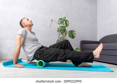 Athlete Man Stretches Using Foam Roller At Home. Man Doing Self-massage Of The Gluteal Muscles With Fascia Roll