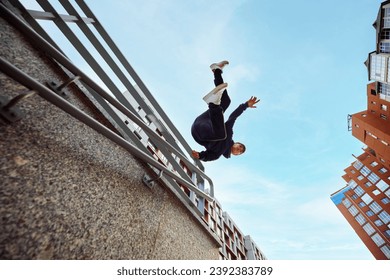 Athlete man, young guy jumping, flips of wall, practice Parkour in public park among high-rise buildings over sunrise. Eye fish filter. Concept of lifestyle, sport, freestyle, activity, motion. Ad - Powered by Shutterstock