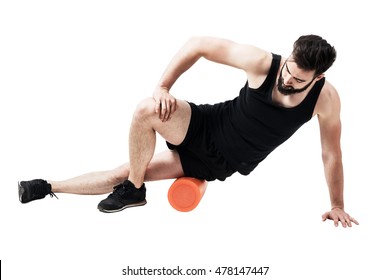Athlete massaging and stretching iliotibial ban muscle with foam roller. Full body length portrait isolated on white studio background. 