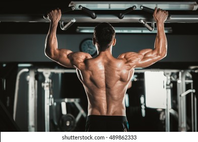 Athlete Muscular Fitness Male Model Pulling Up On Horizontal Bar In A Gym