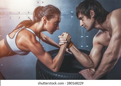 Athlete muscular sportsmen man and woman with hands clasped arm wrestling challenge between a young couple Crossfit fitness sport training lifestyle bodybuilding concept