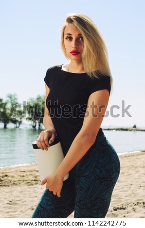 the athlete on the beach posing. blonde girl holding a jar of white , a place for advertising. vitamins sports