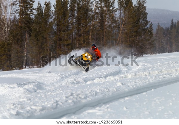 Athlete on a snowmobile moving in the\
winter forest in the mountains of the Southern\
Urals.