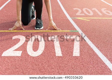 Athlete on starting line waiting for the start in running track with text 2017 year, Start to new year