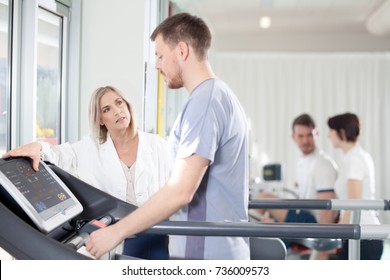 athlete on the treadmill he performs the instructions of physical therapist who assists him. in the background other athletes