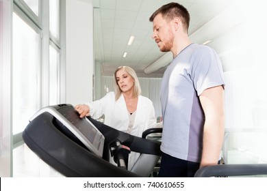 athlete on the treadmill he performs the instructions of physical therapist who assists him. in the background other athletes