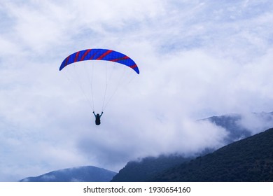 Athlete paragliding against the backdrop of a cloudy sky over the mountains on a summer day.