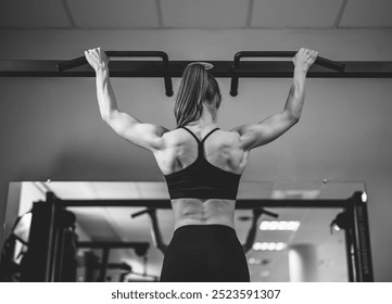 Athlete performing pull-ups in a gym environment. A dedicated athlete completes pull-ups, showcasing strength and determination inside a modern gym space during a workout session. - Powered by Shutterstock