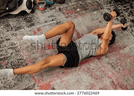 Athlete performs weighted dead bug using dumbbells, enhancing core strength, coordination, and stability during advanced functional training on gym floor.