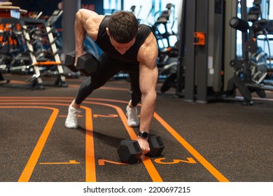 Athlete planking with dumbbells in fitness gym. Athletic man doing gym dumbbell plank row - Powered by Shutterstock