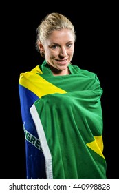 Athlete posing with brazilian flag wrapped around his body on black background