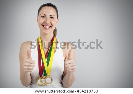 Athlete posing with gold medals around his neck against grey background