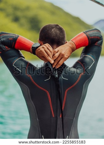 Athlete putting on a swimming suit and preparing for triathlon swimming and training in the river surrounded by natural greenery 商業照片 © 