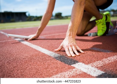 Athlete ready to start the relay race on the running track - Powered by Shutterstock