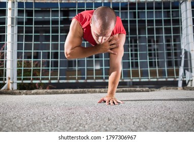 Athlete In A Red T-shirt Doing One Arm Handstand Push Ups At The Outdoor Gym.