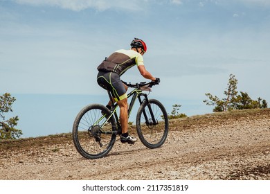 Athlete Riding Uphill Trail On Mountain Bike