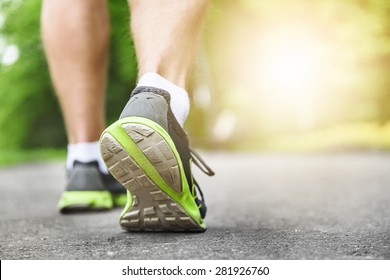 Athlete Runner Feet Running On Road Closeup On Shoe. Man Fitness Sunrise Jog Workout Wellness Concept.