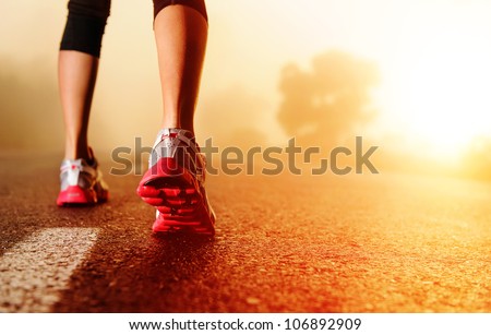 Athlete runner feet running on road closeup on shoe. woman fitness sunrise jog workout wellness concept.