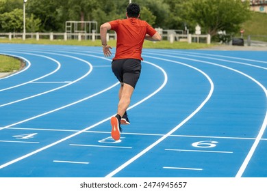 athlete runner is seen from behind while training on a blue athletic track. This image captures the determination and focus of the athlete as they physically and mentally prepare for their competition - Powered by Shutterstock