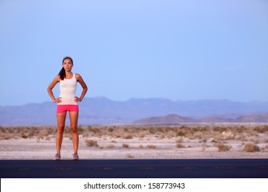 Athlete runner woman resting on road after running on highway in the USA. Beautiful fit fitness girl sweating and relaxing at dusk after a late night run. Mixed race Caucasian Asian female model, 20s.