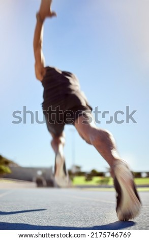 Athlete running on a sports track for fitness exercise in outdoor training practice. Below view of fit active man sprinting motion blur speed. Runner performing cardio workout for health and stamina