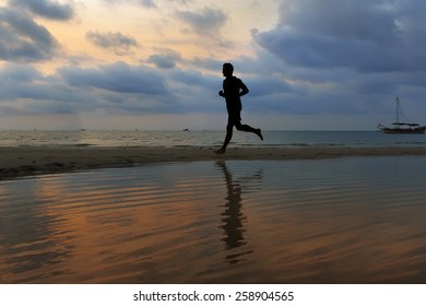 athlete runs along the sand beach with mirror on the water and o - Shutterstock ID 258904565