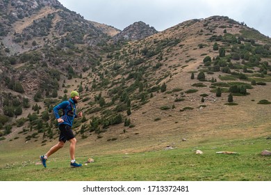 Athlete Runs High In The Mountains Among The Rocks. Bearded Guy Jogging In The Mountains. Trail Running